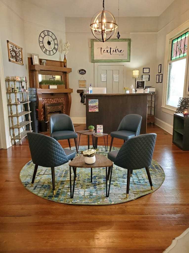 Cozy waiting area with modern chairs, a circular rug, and reception desk in a welcoming office.