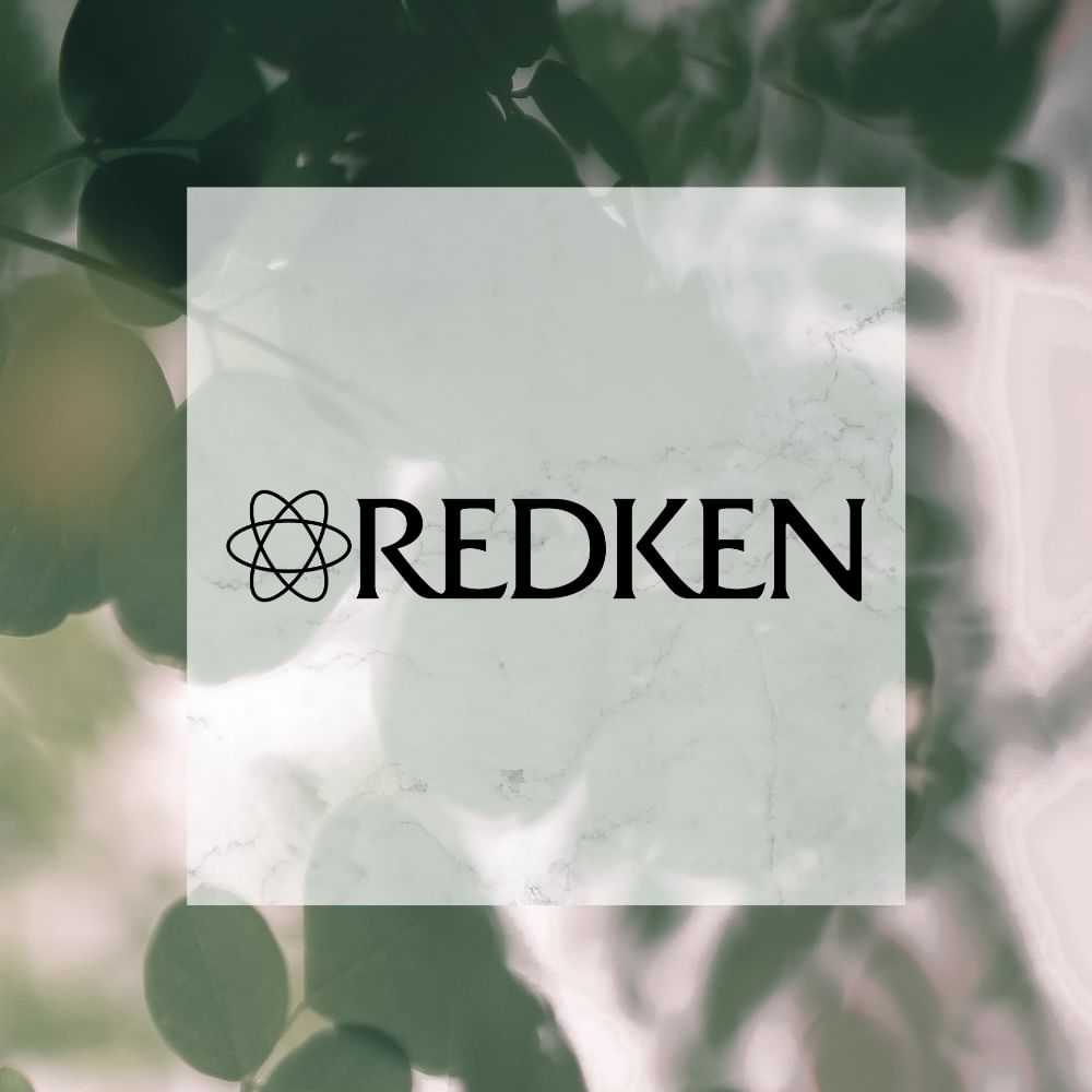 Redken logo with a green leafy background and an atomic symbol next to the brand name.